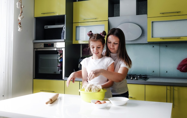 mother and daughter prepare dough together in the kitchen