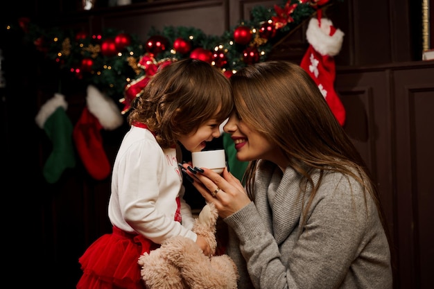 Mother and daughter preparing for christmas celebration. Having fun with family near new year tree. Pregnant woman with daughter.