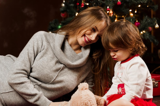 Mother and daughter preparing for christmas celebration. Having fun with family near new year tree. Pregnant woman with daughter.