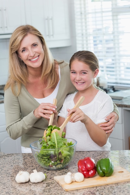 Mother and daughter preparing salad together 