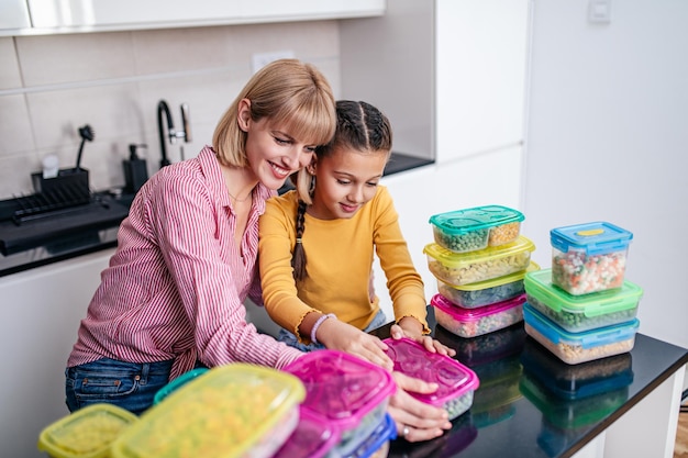 Mother and daughter preparing together vegetables for winter in vacuum containers.