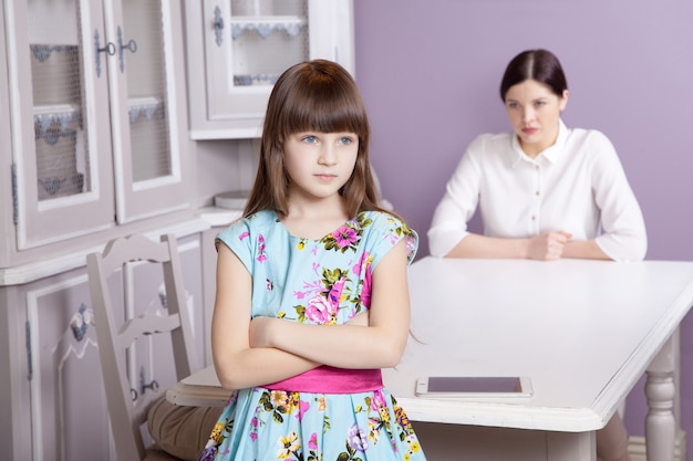 Mother and daughter quarrel because of overuse the tablet phone. Social problem between parents and children. Studio shot..