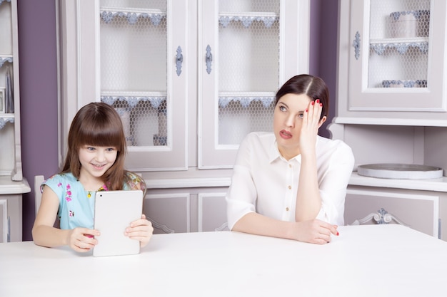 Mother and daughter quarrel because of overuse the tablet phone . Social problem between parents and children. Studio shot..