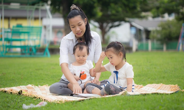 Mother and daughter reading a book together in the park happy\
family and education concept