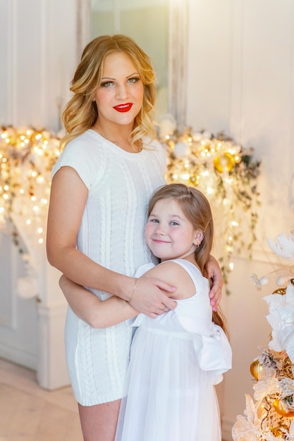 Mother and daughter relax playing near christmas tree at home