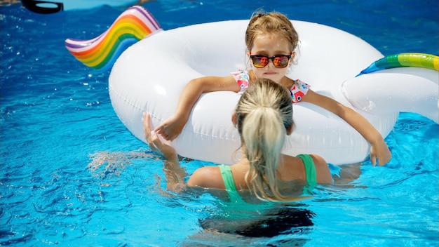 Mother and daughter resting and swimming in a pool in summer