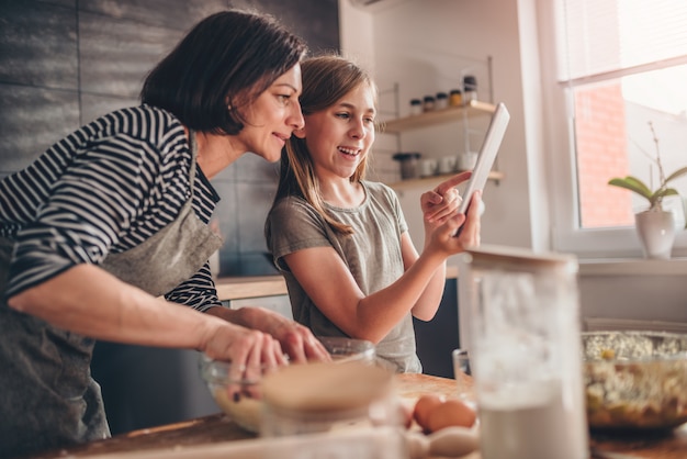 Photo mother and daughter searching apple pie recipe on the tablet