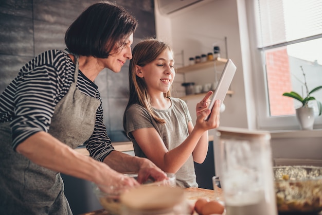 Mother and daughter searching apple pie recipe on the tablet