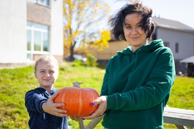 Mother and daughter show a pumpkin they grew at their garden