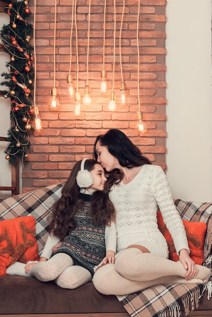 mother and daughter siting on a sofa in Christmas decorated room