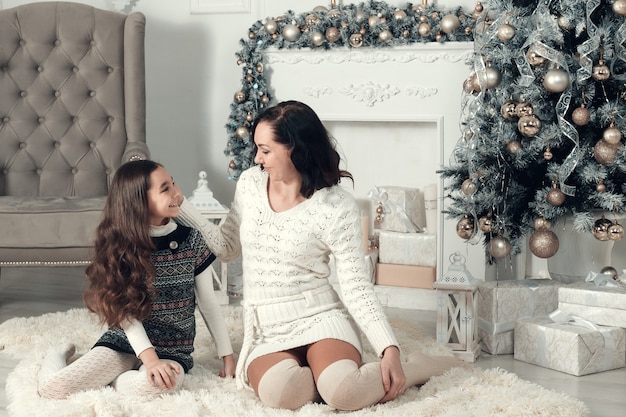 mother and daughter siting on a sofa in Christmas decorated room