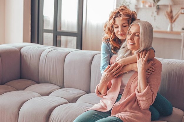 Mother and daughter sitting on the couch and embracing each other