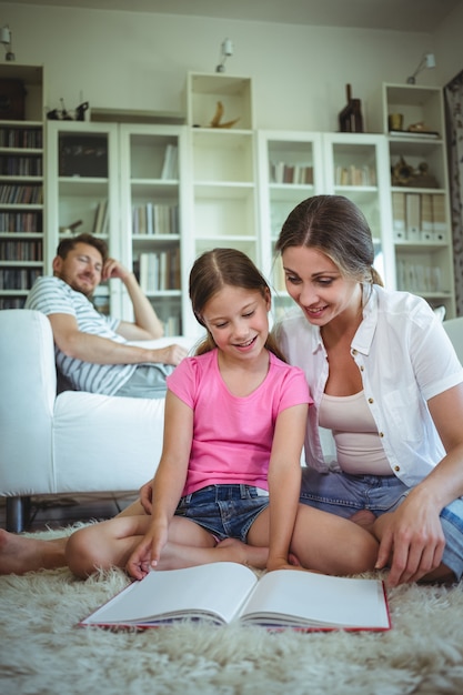 Mother and daughter sitting on the floor and looking at photo album