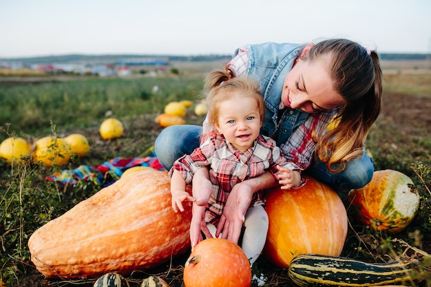 Mother and daughter sitting on pumpkins