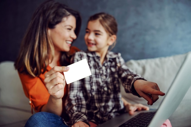 Mother and daughter sitting on the sofa and using laptop for online shopping