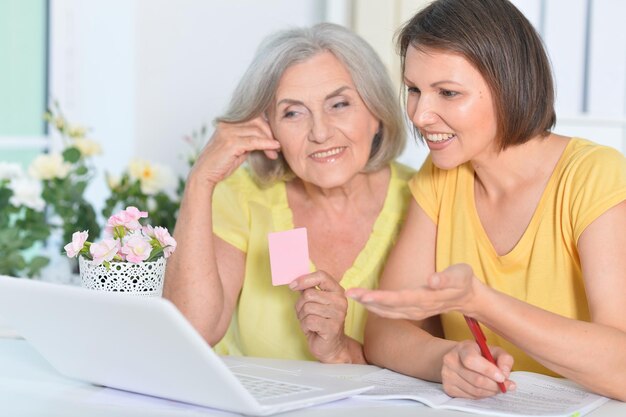 Mother and daughter sitting at table with laptop shopping online