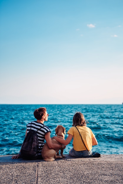 Foto madre e figlia che si siedono sul lungomare con il cane