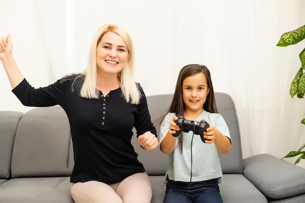 Photo mother and daughter sittingr in a playroom, playing video games and having fun.