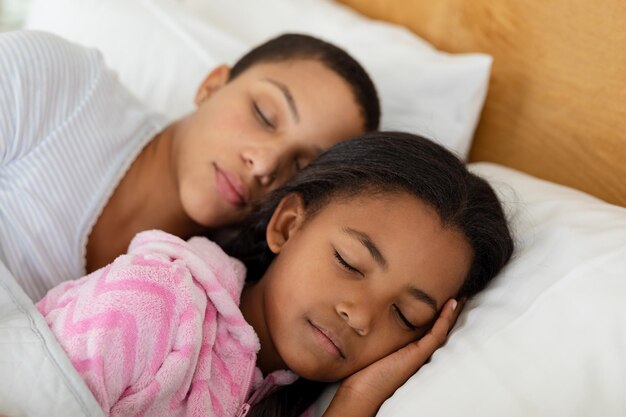 Mother and daughter sleeping together in bed in bedroom