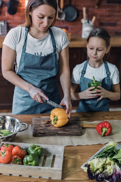 Mother and daughterÃÂ slicing peppers