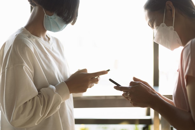 Photo mother and daughter stand with cellphones in a coffee shop to order products on social media