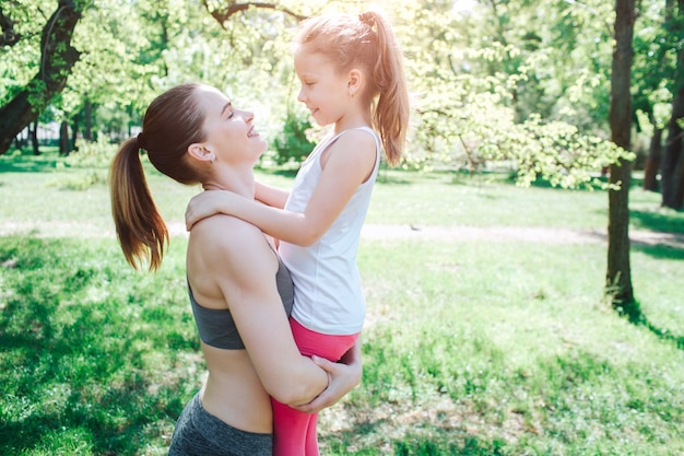 mother and daughter standing outside in park.