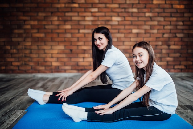 Mother and daughter stretching at home.