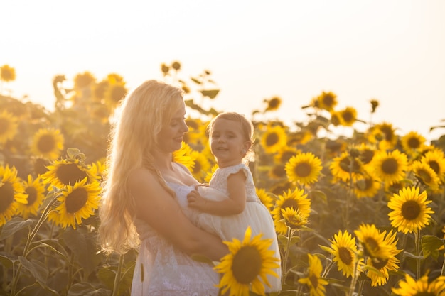 Mother and daughter in a sunflower field like queen and princess of the fields