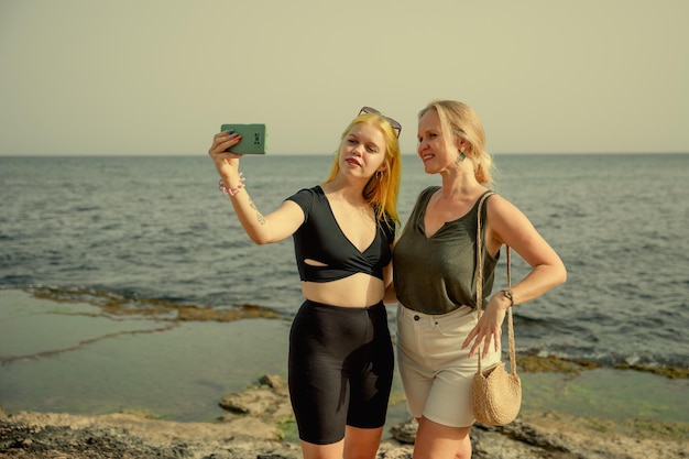 Mother and daughter take selfies against the backdrop of the sea