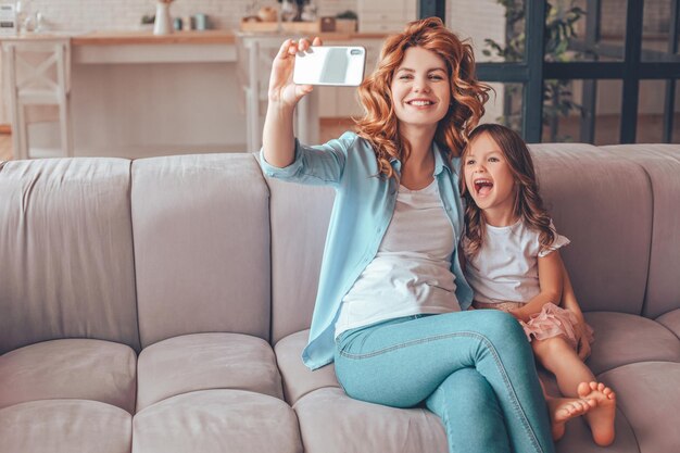 Mother and daughter taking selfie on smartphone at home