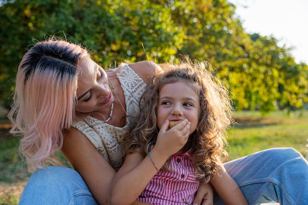 Madre e figlia insieme in un parco su una figlia di picnic che fa uno spuntino