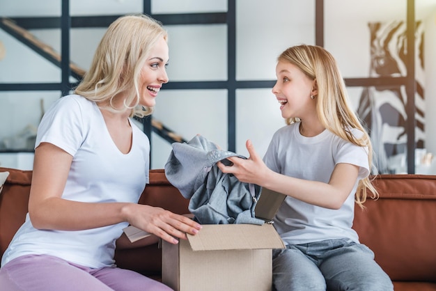 Mother and daughter unpacking cardboard box delivery at home
