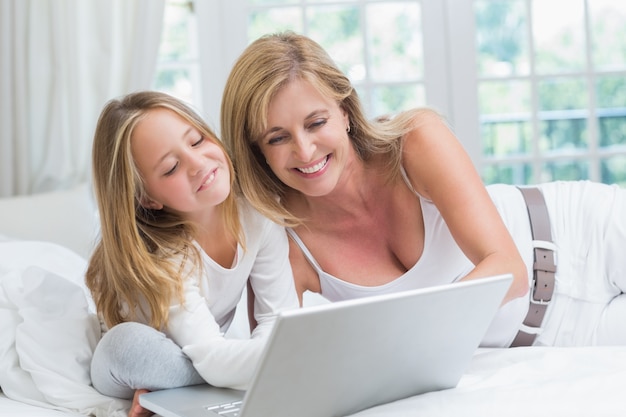 Mother and daughter using laptop in the bed 