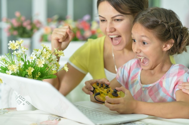 Mother and daughter using laptop playing game