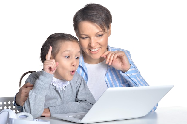 Mother and daughter using laptop posing against white