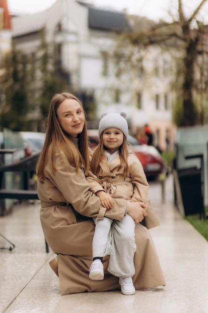 Мать и дочь ходят по городу весны в пальто.