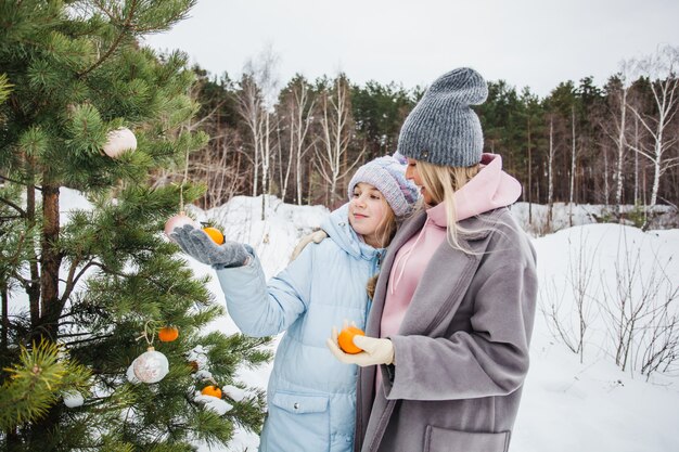 Mother and daughter walking in the winter forest, winter tree, garland, holiday in the forest