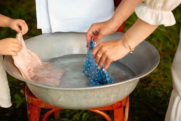 Mother and daughter wash children's clothes in a bowl outdoors