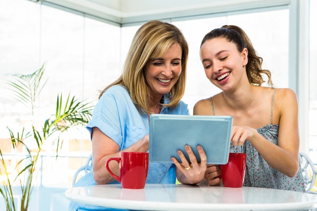 Mother and daughter watch tablet in the kitchen