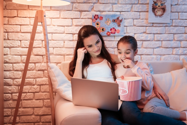 Foto madre e figlia che guardano film e mangiano popcorn.