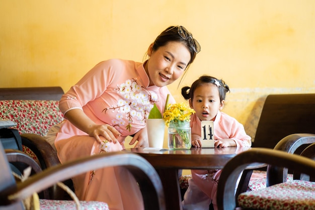 Mother and daughter wearing traditional dress at cafe in hoi an vietnam