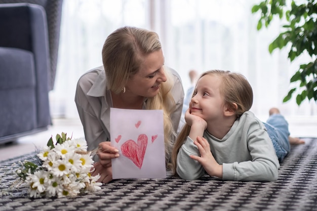 Mother and daughter with card and flower bouquet Mother39s Day birthday or Women39s Day at home