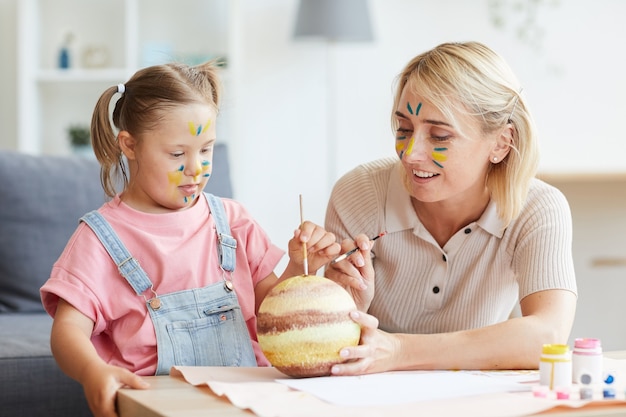 Mother and daughter with down syndrome making crafts together at the table at home