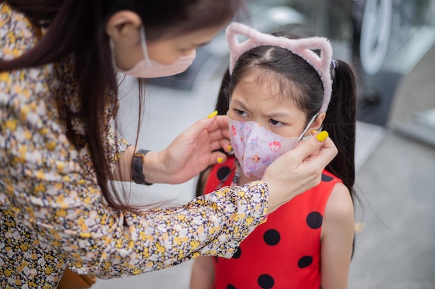 Mother and daughter with face mask in shopping center, coronavirus concept.