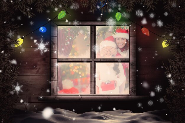 Mother and daughter with gift against christmas home seen through frosty window