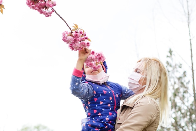 Mother and daughter with masks walking and talking on the street