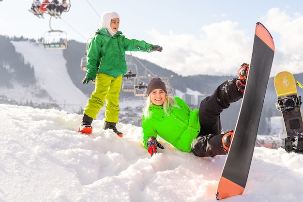 Mother and daughter with snowboards are playing in the snow