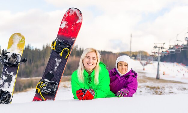 mother and daughter with snowboards at winter resort