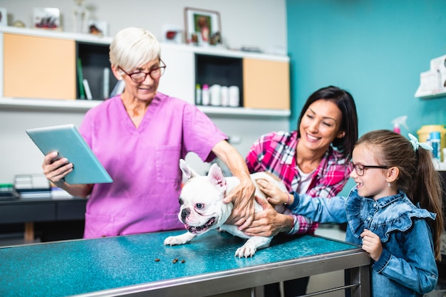 Mother and daughter with their french bulldog at veterinary.