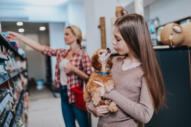 ペットショップでプードルの子犬と母と娘。